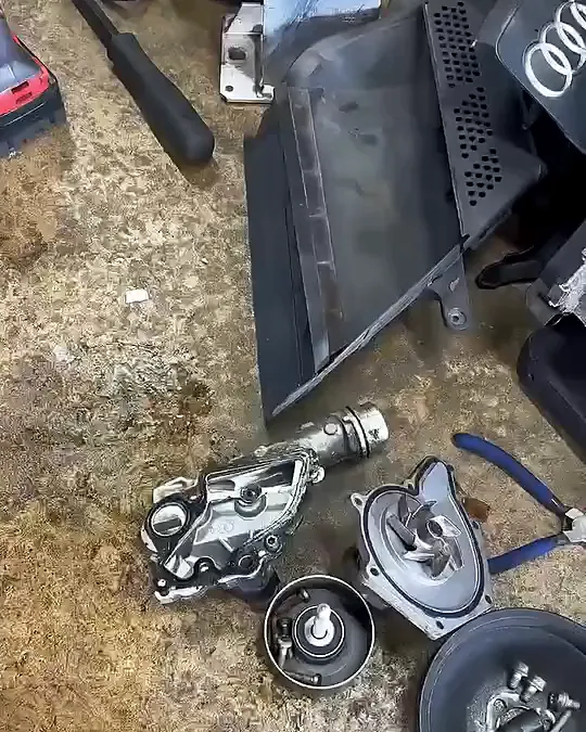 Pulled engine parts and an Audi engine cover laid out on the shop floor