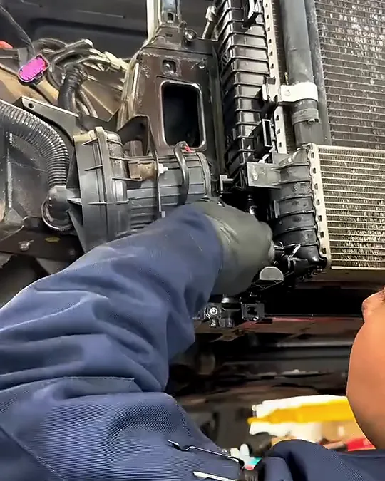 Technician reaching into the Audi front end beside the radiator and cooling stack